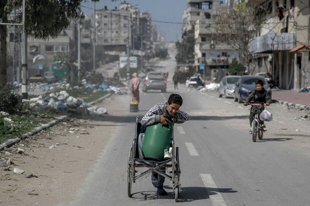 ３日、パレスチナ自治区ガザ市で水を運ぶ少年（ＡＦＰ時事）