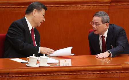 ５日、北京で開かれた中国全国人民代表大会（全人代）で、言葉を交わす習近平国家主席（左）と李強首相（ＥＰＡ時事）