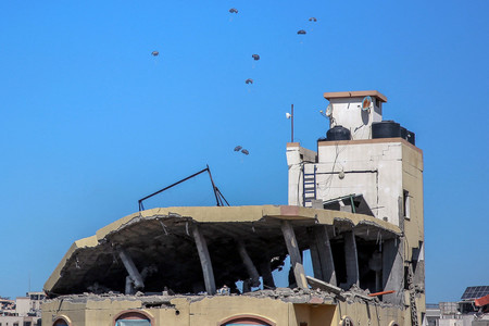 ５日、パレスチナ自治区ガザ北部の上空から投下される支援物資（ＡＦＰ時事）