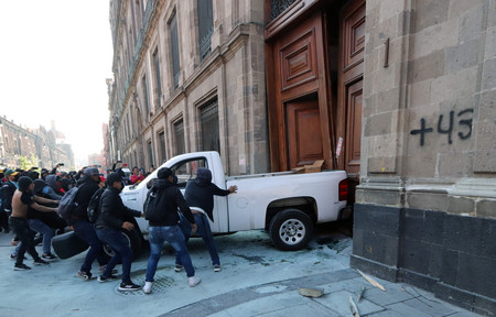 ６日、メキシコの首都メキシコ市で、大統領府の扉を破壊するデモ隊（ＡＦＰ時事）