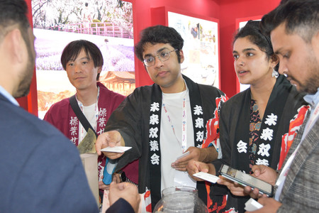 インドの首都ニューデリー郊外で開かれた観光博覧会に参加する（左から）山根辰洋さん、トリシット・バネルジーさん、スワスティカ・ジャジュさん＝２月２３日
