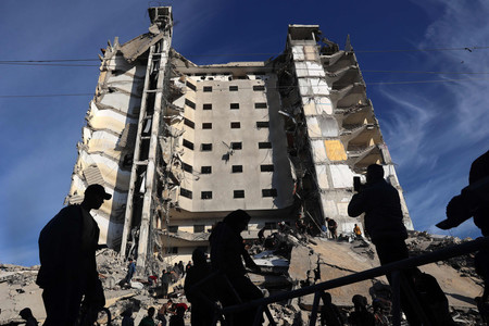 ９日、パレスチナ自治区ガザ南部ラファで、イスラエル軍の攻撃で破壊された集合住宅前に集まる市民（ＡＦＰ時事）
