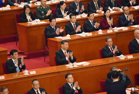 １１日、北京で開かれた中国の全国人民代表大会（全人代）の閉幕式で、議案可決後に拍手する習近平国家主席（中央）
