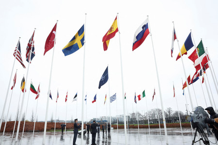 １１日、ブリュッセルの北大西洋条約機構（ＮＡＴＯ）本部で行われた式典で掲揚されるスウェーデン国旗（中央左）（ロイター時事）