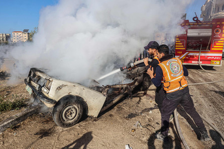 １３日、パレスチナ自治区ガザ最南部のラファで、イスラエル軍の攻撃で炎上した車の消火に当たる消防隊員（ＡＦＰ時事）