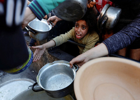 １３日、パレスチナ自治区ガザ最南部ラファで食料の配給を待つ市民（ロイター時事）