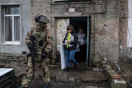 １４日、ロシア占領下のウクライナ東部ドネツクで、武装した兵士と共に有権者宅を訪問する選管当局者（ＡＦＰ時事）