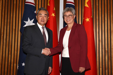 ２０日、キャンベラで握手する中国の王毅共産党政治局員兼外相（左）とオーストラリアのウォン外相（ＡＦＰ時事）