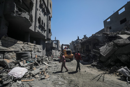 ２０日、パレスチナ自治区ガザのヌセイラト難民キャンプで、破壊された住宅の残骸から行方不明者を捜す人々（ＥＰＡ時事）