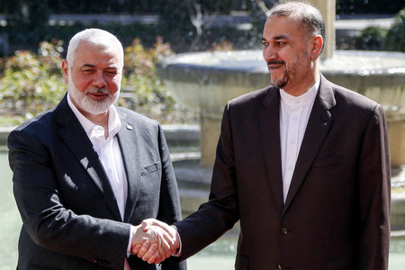 ２６日、テヘランで握手するイスラム組織ハマスの最高指導者ハニヤ氏（左）とイランのアブドラヒアン外相（ＡＦＰ時事）