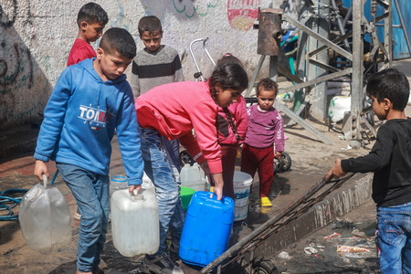 ３０日、パレスチナ自治区ガザ南部ラファで水をくむ子供たち（ＡＦＰ時事）