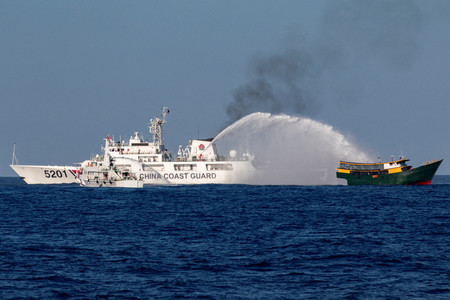 南シナ海のアユンギン（中国名・仁愛）礁近くで、フィリピン船（右）に向け放水銃を発射する中国船＝３月５日（ロイター時事）