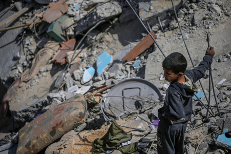３月３１日、パレスチナ自治区ガザの難民キャンプで空爆によって破壊された家を見詰める少年（ＥＰＡ時事）