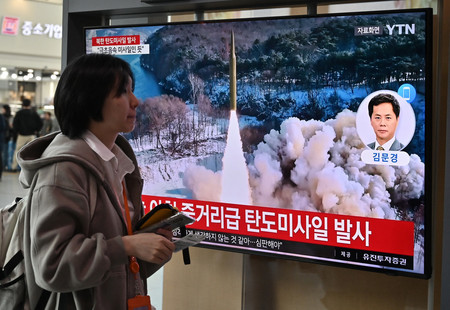 ２日、ソウルの鉄道駅で、北朝鮮のミサイル発射を報じるテレビ画面の前を通る女性（ＡＦＰ時事）