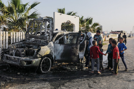 ２日、パレスチナ自治区ガザ中部で破壊された国際ＮＧＯ「ワールド・セントラル・キッチン（ＷＣＫ）」の車を見詰める人々（ＥＰＡ時事）
