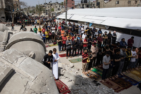５日、パレスチナ自治区ガザ南部ラファの破壊されたモスク（イスラム礼拝所）の脇で金曜礼拝に臨む人々（ＥＰＡ時事）