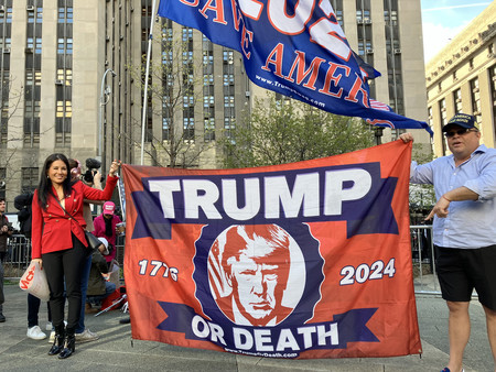 １５日、米ニューヨーク市の裁判所前で旗を掲げるトランプ前大統領の支持者