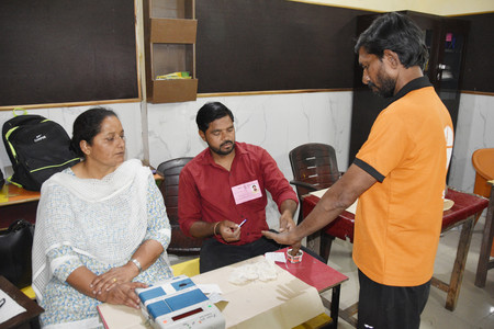 １９日、インド北部ウッタルプラデシュ州ラームプルの投票所で、投票を終えたしるしのインクを指に塗られる有権者（右）