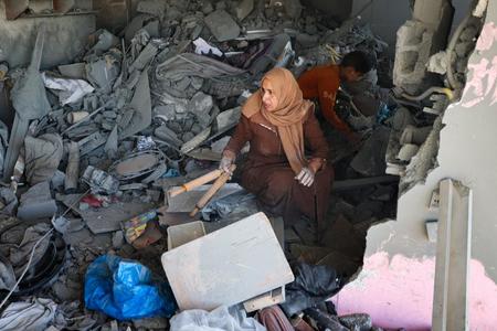 イスラエルによる攻撃で破壊された家のがれきの中から物を探す女性＝２０日、パレスチナ自治区ガザ最南部ラファ（ＡＦＰ時事）