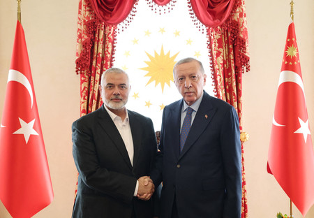 ２０日、イスタンブールで握手を交わすトルコのエルドアン大統領（右）とイスラム組織ハマスの最高指導者ハニヤ氏＝トルコ大統領府提供（ＡＦＰ時事）