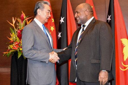 ２１日、ポートモレスビーでパプアニューギニアのマラペ首相（右）と握手する中国の王毅共産党政治局員兼外相（ＡＦＰ時事）