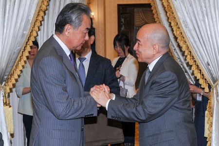 ２１日、プノンペンで握手するカンボジアのシハモニ国王（右）と中国の王毅共産党政治局員兼外相（ＡＦＰ時事）