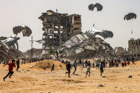 ２３日、パレスチナ自治区ガザ北部で、空中投下された人道支援物資に群がる住民（ＡＦＰ時事）