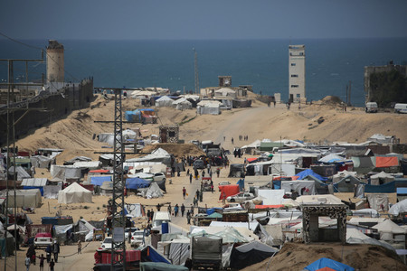 ２８日、パレスチナ自治区ガザ最南部ラファで避難民のテントの間を歩く人々（ＡＦＰ時事）
