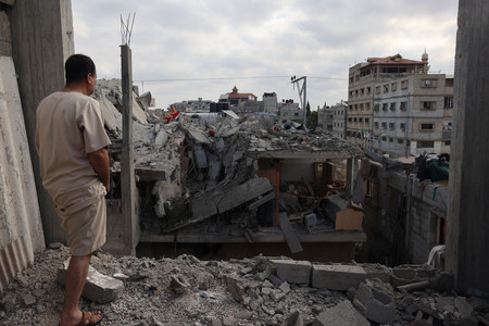 ２９日、パレスチナ自治区ガザ最南部ラファで、イスラエルの攻撃を受け崩壊した建物を見詰める男性（ＡＦＰ時事）