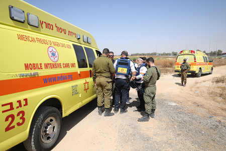 ５日、パレスチナ自治区ガザとの境界にあるイスラエル南部ケレム・シャローム検問所付近に集まる救急隊員と兵士ら（ＥＰＡ時事）