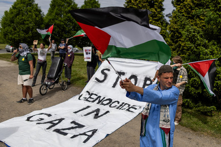 ６日、ポーランド南部オシフィエンチムで、パレスチナの旗や「ガザでの大量虐殺をやめろ」と記された垂れ幕を掲げるデモ参加者（ＡＦＰ時事）