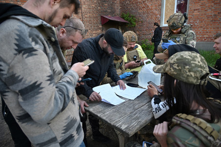 １０日、ウクライナ北東部ハリコフ州で、避難計画を相談する市民（ＡＦＰ時事）