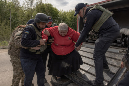 １４日、前線に近いウクライナ北東部ハリコフ州の集落から避難し、州都ハリコフ郊外の検問所に到着した女性（中央）（ＡＦＰ時事）