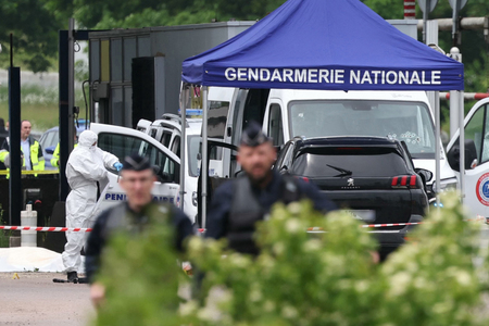 銃弾が撃ち込まれた護送車の周辺を調べる警察官＝１４日、フランス北部ルーアン郊外（ＡＦＰ時事）