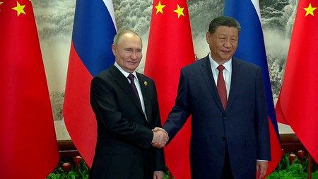 １６日、北京で握手するロシアのプーチン大統領（左）と中国の習近平国家主席（ロシア大統領府の中継映像より）（ロイター時事）