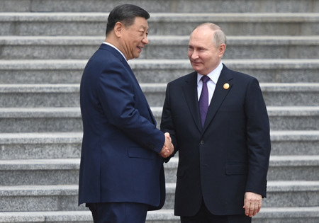 １６日、北京で開かれた歓迎式典で握手する中国の習近平国家主席（左）とロシアのプーチン大統領（ロイター時事）