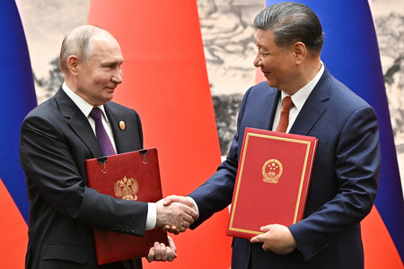１６日、北京で握手する中国の習近平国家主席（右）とロシアのプーチン大統領（ＥＰＡ時事）