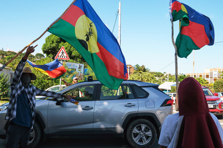 フランス領ニューカレドニアで独立派勢力の旗を掲げる人々＝１３日、ヌメア（ＡＦＰ時事）