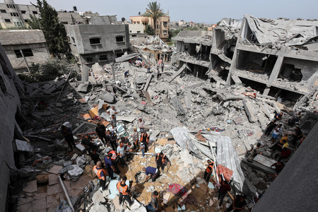 １９日、パレスチナ自治区ガザ中部ヌセイラトで、イスラエル軍の攻撃で破壊された家屋を調べる住民（ロイター時事）