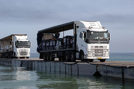パレスチナ自治区ガザに設置された浮桟橋を通る、支援物資を積んだトラック＝アラブ首長国連邦（ＵＡＥ）の国営首長国通信（ＷＡＭ）が１９日公開（ＡＦＰ時事）