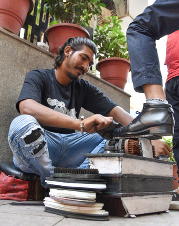インドの首都ニューデリーで靴磨きの仕事をするバブル・シンさん＝２１日