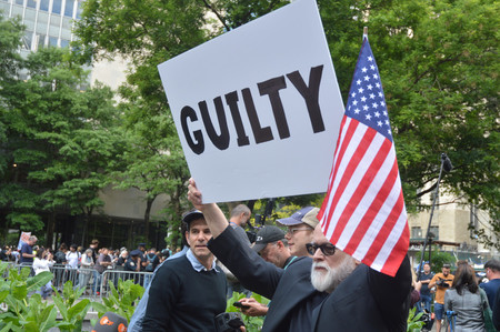 「ＧＵＩＬＴＹ（有罪）」と書かれたプラカードを掲げる米民主党の支持者＝３０日、ニューヨーク
