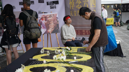 ４日、台北市で開かれた天安門事件の追悼集会で、献花台に花を手向けメッセージを寄せる参加者