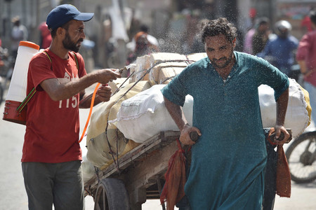 猛暑の中、通行する人々に水を掛ける福祉団体の職員＝５月３０日、パキスタン南部カラチ（ＥＰＡ時事）