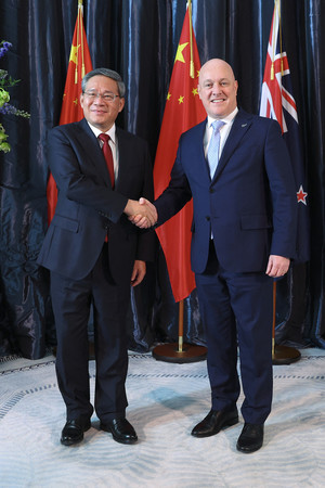 １３日、ウェリントンで握手する中国の李強首相（左）とニュージーランドのラクソン首相（ＡＦＰ時事）