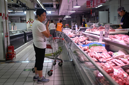 北京のスーパーで、豚肉を選ぶ女性＝１２日（ＡＦＰ時事）
