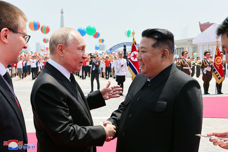 １９日、平壌の金日成広場でロシアのプーチン大統領（左）と握手する北朝鮮の金正恩朝鮮労働党総書記＝朝鮮中央通信が２０日配信（ＡＦＰ時事）