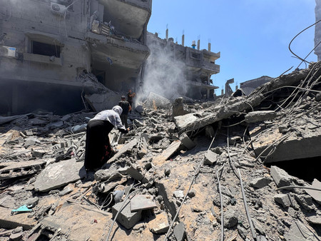 ２２日、パレスチナ自治区ガザ北部のガザ市で、イスラエルの空爆を受けた建物で救助に当たる住民（ロイター時事）