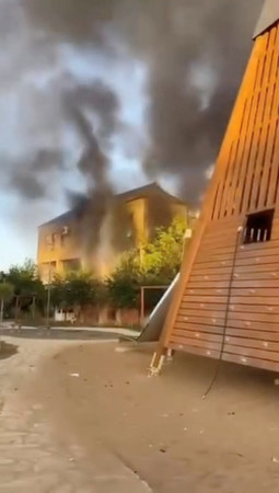 ２３日、ロシア南部ダゲスタン共和国デルベントで、黒煙が立ち上る建物（ロイター時事）