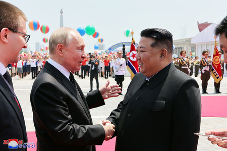１９日、平壌の金日成広場で行われた歓迎式典で握手を交わす金正恩朝鮮労働党総書記（右）とロシアのプーチン大統領（朝鮮通信＝時事）